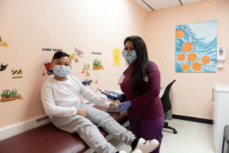 a young boy sitting on an exam table while a doctor checks his pulse