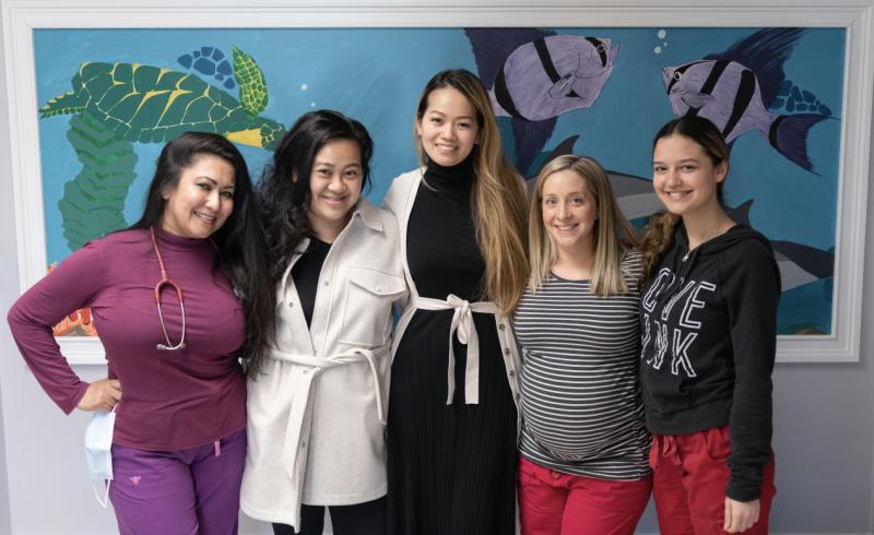 Five women stand in front of painting