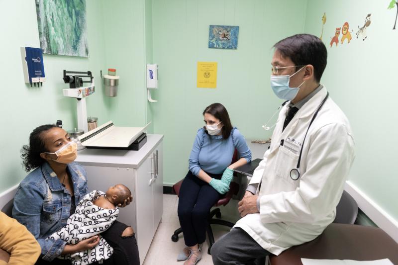 Mom holds baby, with doctor and assistant